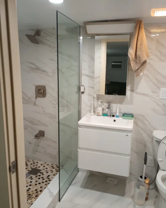 Finished bathroom with marble tile, glass shower and white vanity