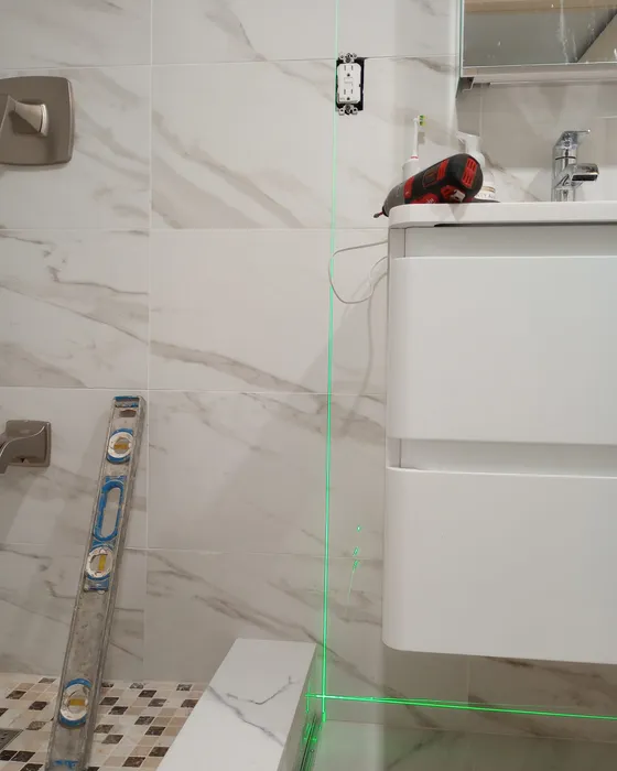 Wall-mounted vanity being leveled in a tiled bathroom